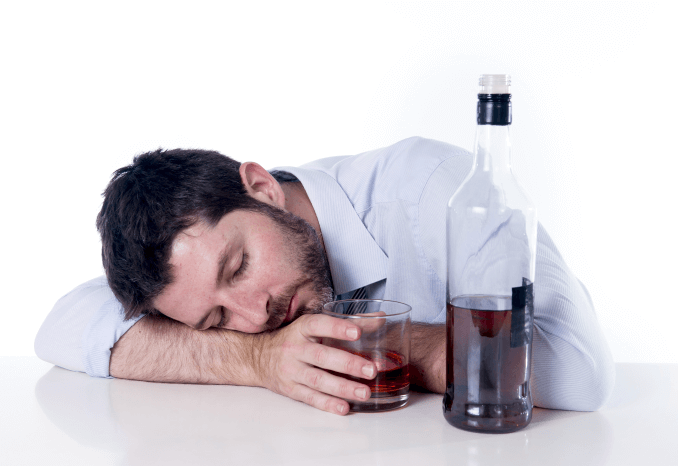 Выпивший мужчина уснул на столе с бутылкой