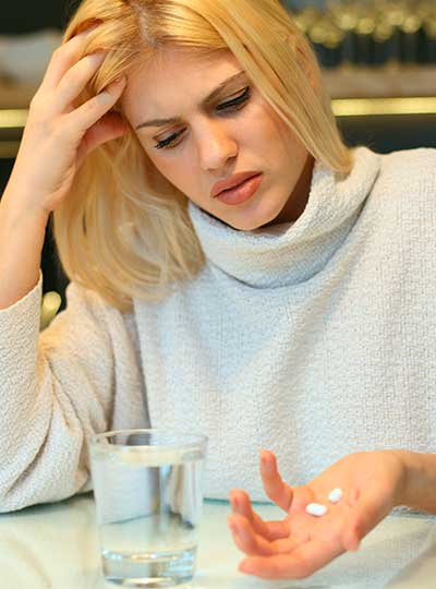 женщина сидит за столом с таблетками в руке